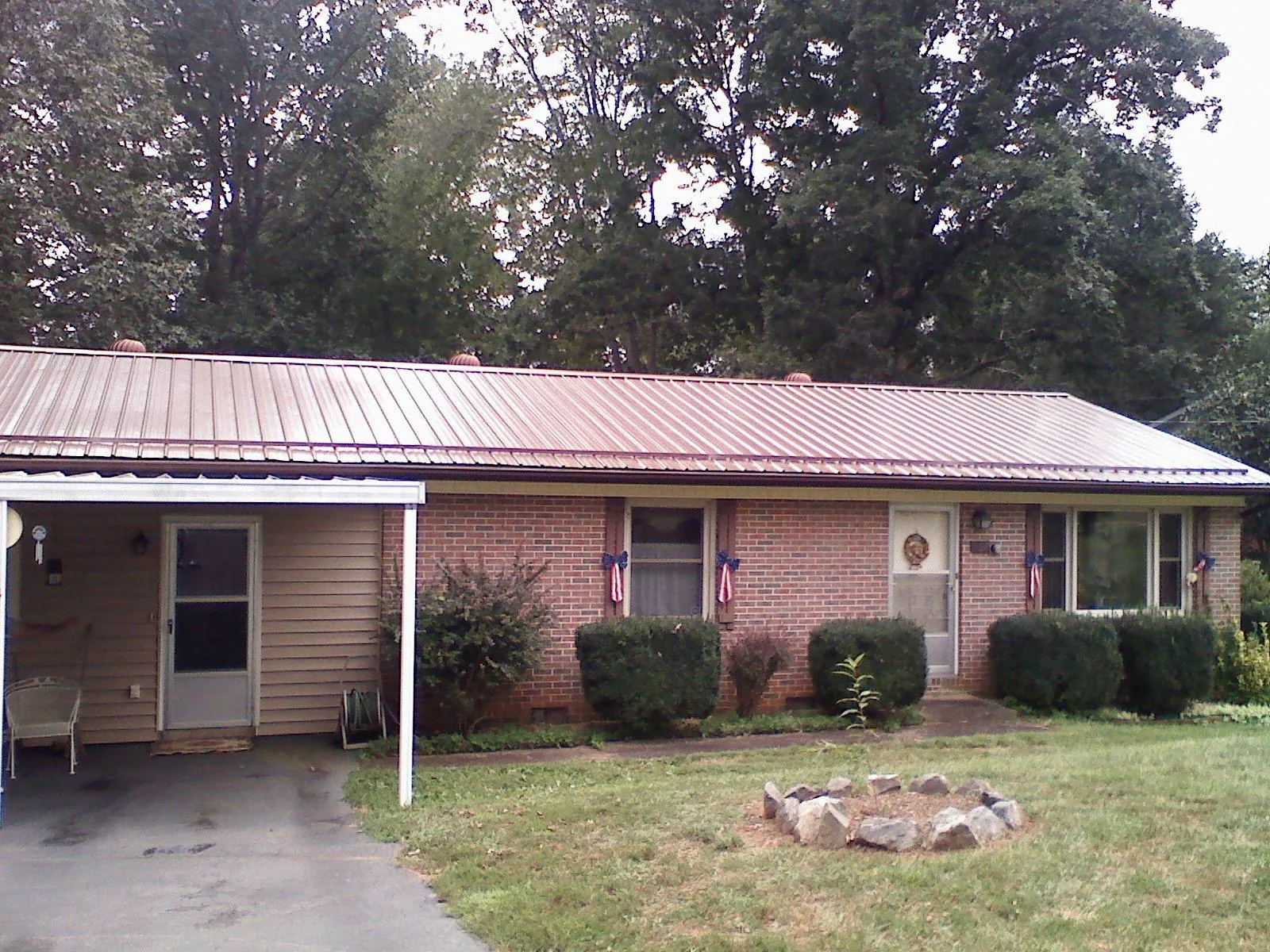Bronze metal roof and carport on a brick ranch home — Roof Repair work by our crew in Laurel