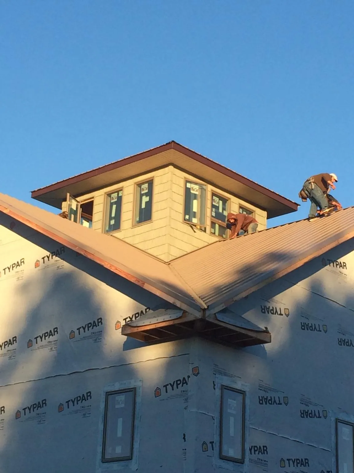 Roofers working around a rooftop cupola on a new metal roof at sunset — Roof Waterproofing in Laurel by Roofing Brothers